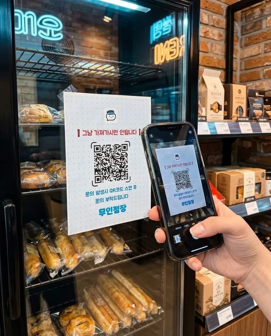 무인매장 진열대에 붙은 무인점장 QR 안내문을 손님이 휴대폰으로 스캔하는 모습